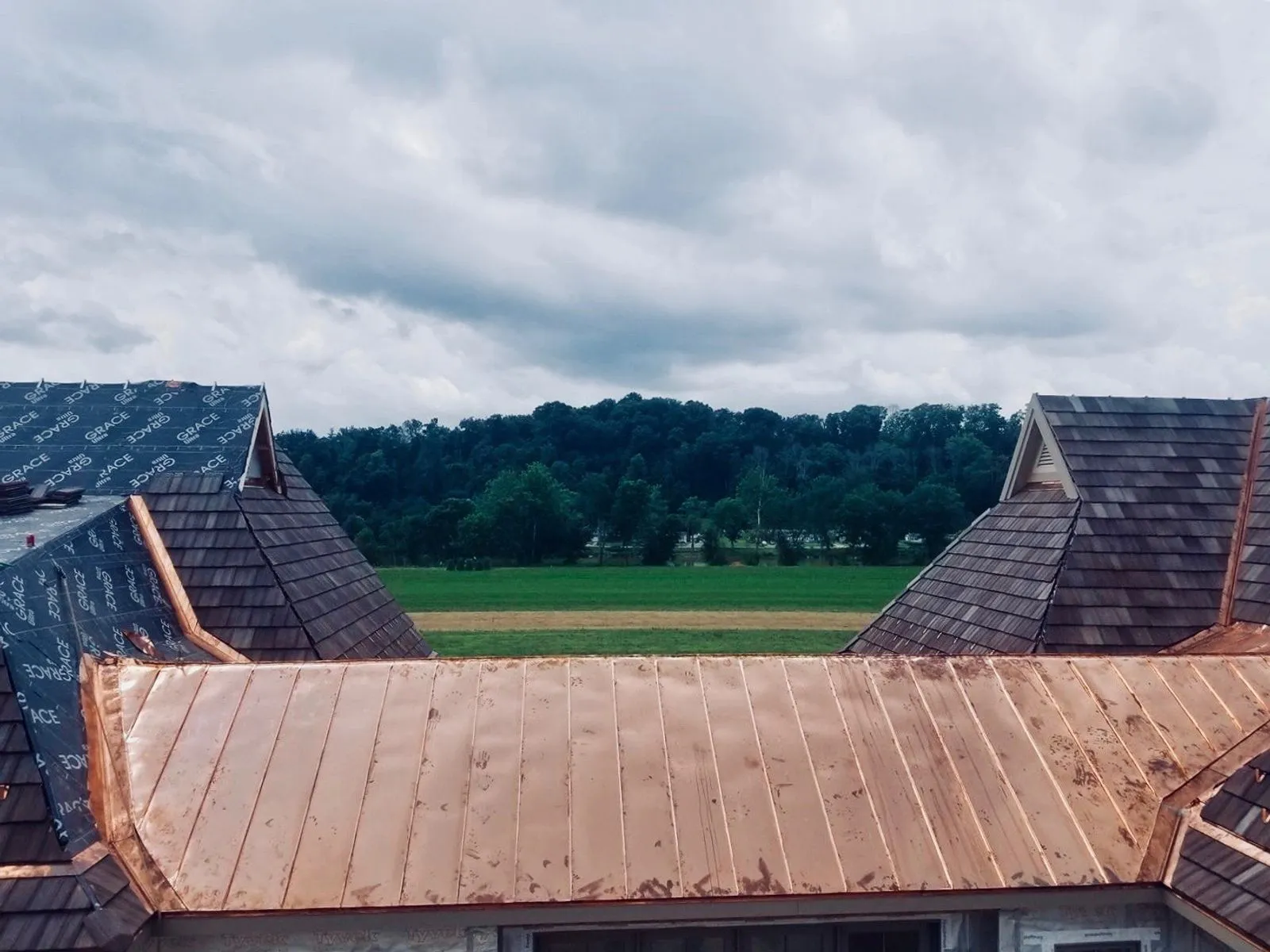 A copper standing-seam valley running against cedar shake roofing